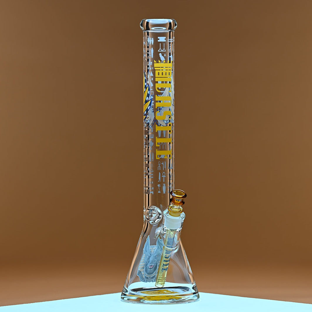 A glass bong with yellow accents, featuring the brand name Castle in bold yellow letters along with Egyptian hieroglyphics on the neck. It is set against a warm amber background that enhances the vibrant yellow details and the amber-tinted bowl and downstem. The clean lines of the glass and the intricate design elements are highlighted, creating a visually striking contrast against the simple, warm backdrop.