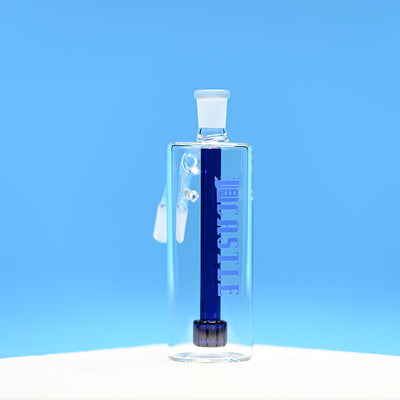 A glass ash catcher featuring the brand name Castle in bold blue letters on the side, with a matching blue matrix percolator. The ash catcher is positioned against a bright blue background, which enhances the deep blue color of the percolator and the branding. The clean lines and transparent glass design are prominently displayed, highlighting the modern and sophisticated craftsmanship of the piece.
