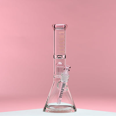 A clear glass beaker bong with pink accents and the Castle Glassworks logo on the neck. The bong features an eight-arm percolator and is set against a soft pink background, showcasing its elegant design and intricate details. The image highlights the craftsmanship and quality of the piece, presenting a clean and modern aesthetic.