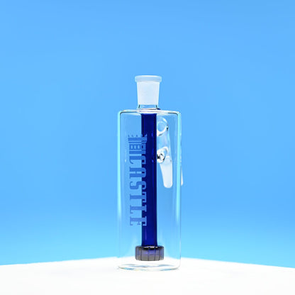 The image shows a clear glass ash catcher with a dark blue showerhead percolator inside. The ash catcher has the brand name "CASTLE" vertically on the front. The background is a solid, vibrant blue, which contrasts sharply with the dark blue percolator inside the ash catcher. The ash catcher is placed on a white surface, and the photo is taken from a front-facing angle, emphasizing the clarity of the glass and the deep color of the percolator.