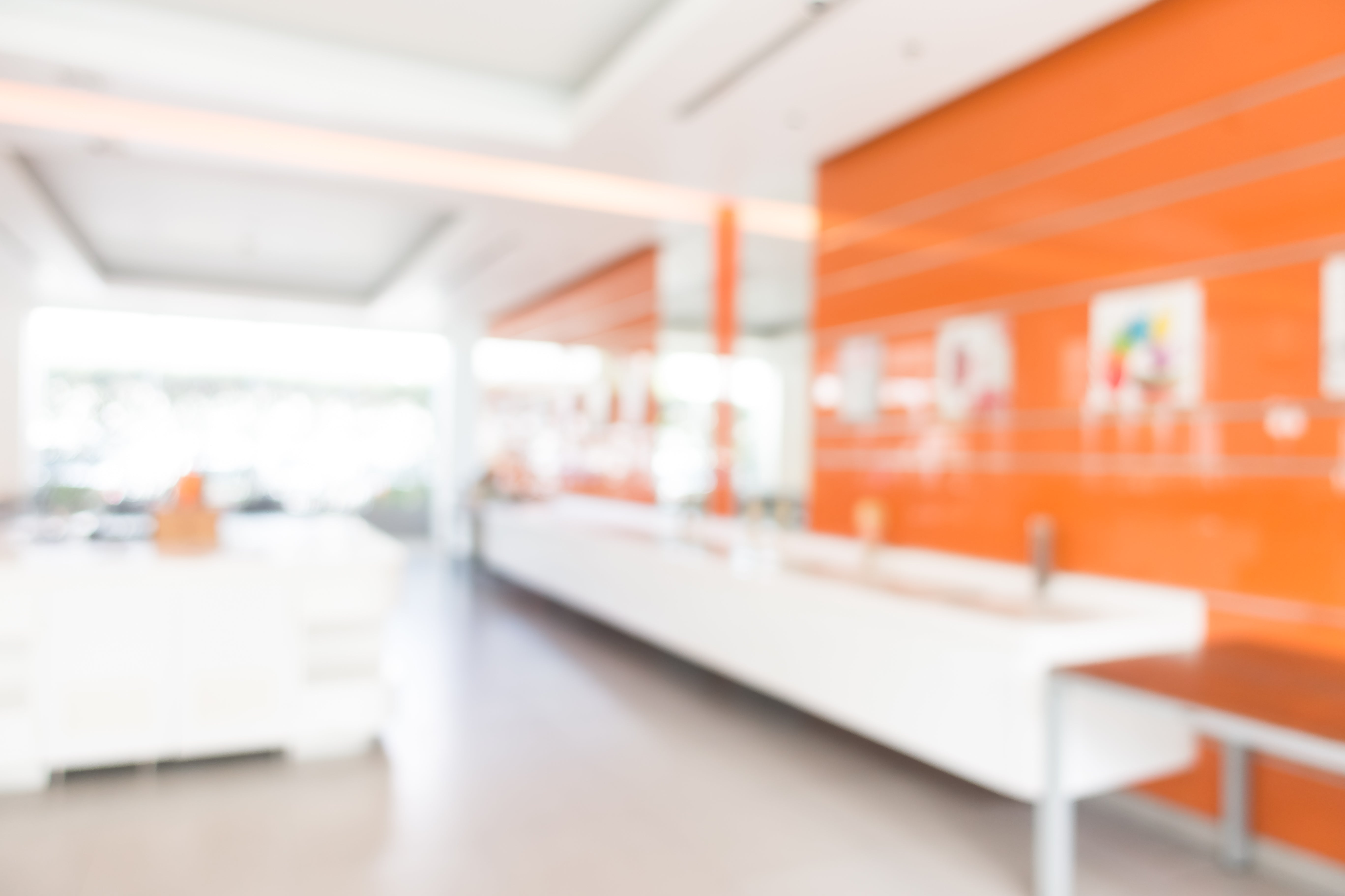 Bright, modern interior with an orange accent wall and white counters, shown in a soft, blurred focus.